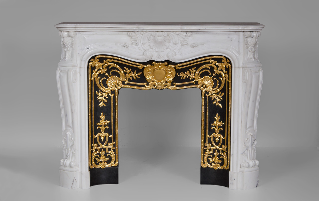 “Madame Du Barry” is a custom-made Louis XV style marble fireplace of a rare opulence.
The generously curved shape is elaborately decorated with finely carved plant motifs. The center of the entablature of this custom fireplace is decorated with a large floral shell, a motif that we find again on the tops of the jambs. The jambs, feature a curved shape, and a rolled up design towards the top.
