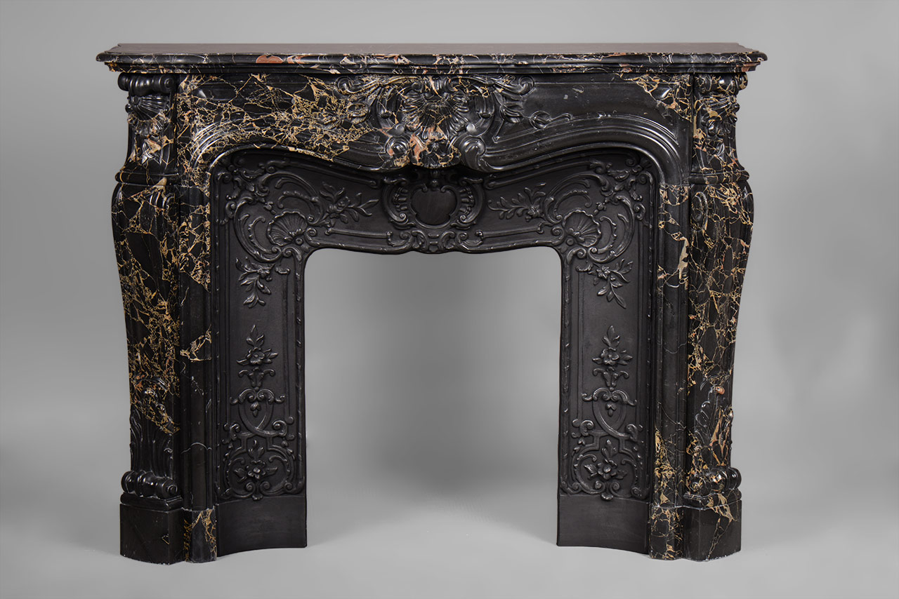 “Madame Du Barry” is a custom-made Louis XV style marble fireplace of a rare opulence.
The generously curved shape is elaborately decorated with finely carved plant motifs. The center of the entablature of this custom fireplace is decorated with a large floral shell, a motif that we find again on the tops of the jambs. The jambs, feature a curved shape, and a rolled up design towards the top.
